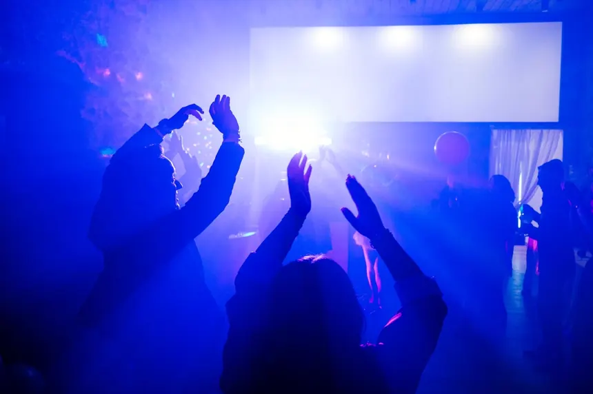 Pista de baile llena con luces y manos arriba en una fiesta de cumpleaños